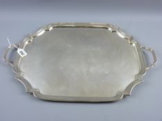 An oblong uninscribed silver tray with shaped corners and end handles, 59 ozs, Birmingham 1954