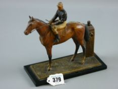 A spelter cold painted figure table lighter of a racehorse with a jockey up on a black glass base (