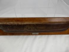 A wall mounted item in the form of a ship's hull, the teak being from HMS Champion, built by