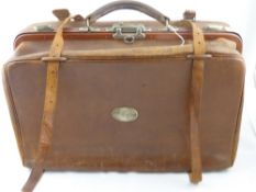 A vintage leather travelling case having a metal plaque to one side  