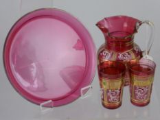 An Antique Bohemian Cranberry Water Jug with hand painted floral design with two matching tumblers