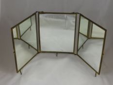 An Edwardian three panel screen vanity mirror having an ivorine panel depicting cherubs.