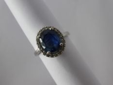An 18 ct White Gold Sapphire and Diamond Cluster Ring, the central oval sapphire 9.6 x 7.7 mm, 3.
