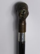 An Ebonised Walking Cane, with large bronze Negro's head (detachable, unscrews) with silver collar