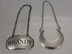 A Georgian Solid Silver Brandy Label, mm TO together with a moon shaped Port label, Birmingham