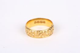 An 18ct gold wedding band, decorated all round with flower heads. 5.9 grams. Size O ½ . Good