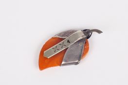 An amber dress clip, the shaped amber in the form of a leaf within a white metal coloured mount