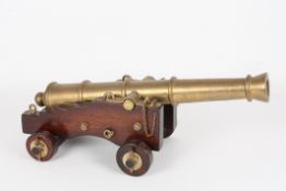 A 19th century brass and wood model of a cannonwith 74cm tapering barrel, mounted on a stepped