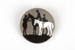 An Art Deco silver and enamel circular broochdecorated with a silhouette scene of figures on