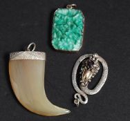 A collection of Three oriental silver pendants one jade with carved foliate design one tooth with