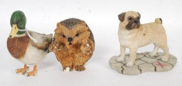 A collection of three vintage ceramic figures including a hedgehog, pug dog and a mallard duck.