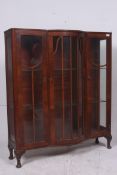 A 1930's serpentine walnut and glass fronted bookcase display cabinet. Raised on cabriole legs