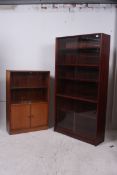 A 1930's walnut bookcase having sliding glass doors over twin door cupboard together with another