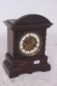 An Edwardian oak cased brass and enamel faced mantel clock. The gingerbread style case with 8 day
