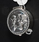 A white metal ( 925 silver ) pill box with embossed cherubs to the lid