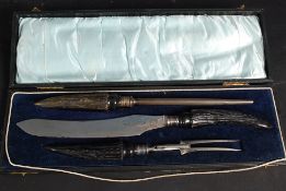 A cased three piece ebonised horn handled carving set by Walker and Hall