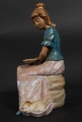 A good Spanish Nao figurine of a seated girl having glazed finish.