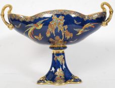 A Carltonware twin handled vase decorated with a bird of paradise standing amongst trees,