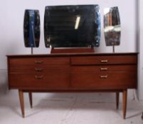 A retro 1970's teak wood dressing table having triptych mirror over drawers being raised on tapered