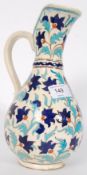 A Persian ? Iznik style glazed pottery jug having polychrome decorated finish of scroll work on a