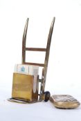 A vintage novelty match box holder in the form of a sack truck along with a vintage brass vesta