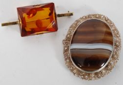 An polished agate stone silver mounted brooch along with a amber silver mounted brooch.