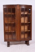 A 1930's Art Deco oak display cabinet having shaped feet with twin doors and a shelved interior.