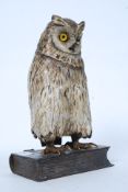 A large bronze cold painted owl with glass eyes set on a plinth base in the form of a book having