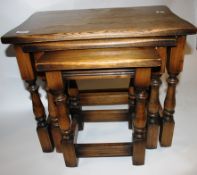 A Jacobean revival oak nest of tables raised on turned supports united by stretchers on block feet