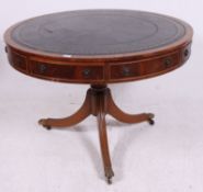 A regency style large mahogany and leather drum table raised on reeded tripod base with gilt tooled