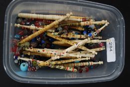 A collection of early bone and glass bead needlework bobbins having ribbed and tapered design,