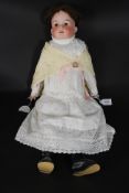 An Edwardian Armand Marseille bisque shoulder and head doll with  brown glass eyes,