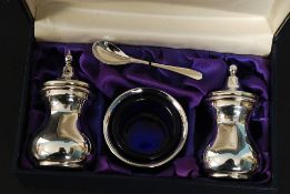 A hallmarked silver set of salts / condiment shakers, spoon and blue glass lined mustard pot.