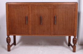 A 1930's Art Deco oak sideboard raised on turned legs having sliding doors revealing an inner chest