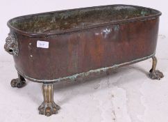 A Victorian copper planter with lion faced handles (hoops missing), standing on claw feet.