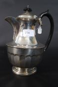 A silver hallmarked coffee pot of large proportions by Kemp Brothers having ebonised swirl handle