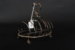 A good Victorian silver plated toast rack of rococo form having hoof feet with pierced handle atop.