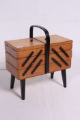 A vintage 1950's beech wood metamorphic sewing box having tapered legs with handle atop.
