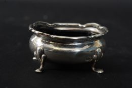 A silver hallmarked table salt raised on hoof feet with blue glass liner by Adie Bros,