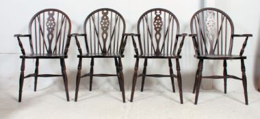 A set of four 20th century beech wood contemporary wheelback carver dining chairs being raised on