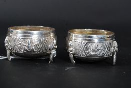 A pair of siam silver thai table salts cast in relief with deitys raised on serpent legs. Weight 74.