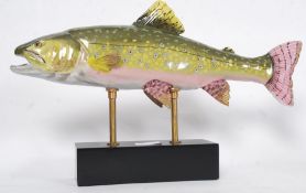 A large ceramic figurine of a salmon raised on a plinth rectangular base.
