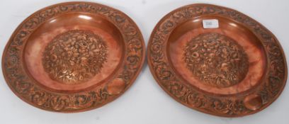 A pair of 19th century copper Newlyn style chargers moulded in relief with scroll work to the