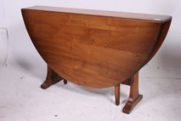 An Ercol large beech and elm drop leaf dining table having oval leaves with gate leg supports.