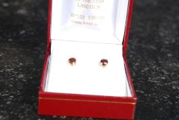A 9ct gold ladies pair of round faceted garnet stud earrings