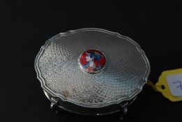 A silver and enamel set trinket box of circular form having chase decoration with inset enamel