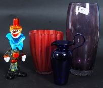 A collection of coloured glass items to include a Murano glass clown, purple glass vase,