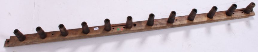 A large 20th century Industrial coat rack, the pegs of unusual form mounted to planked rear.