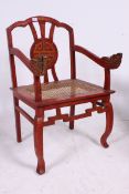 A 20th century Chinese caned horseshoe chair raised on squared supports with caned seat having red