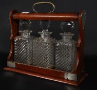 An early 20th century oak and silver plate tantalus complete with the 3 glass decanters.